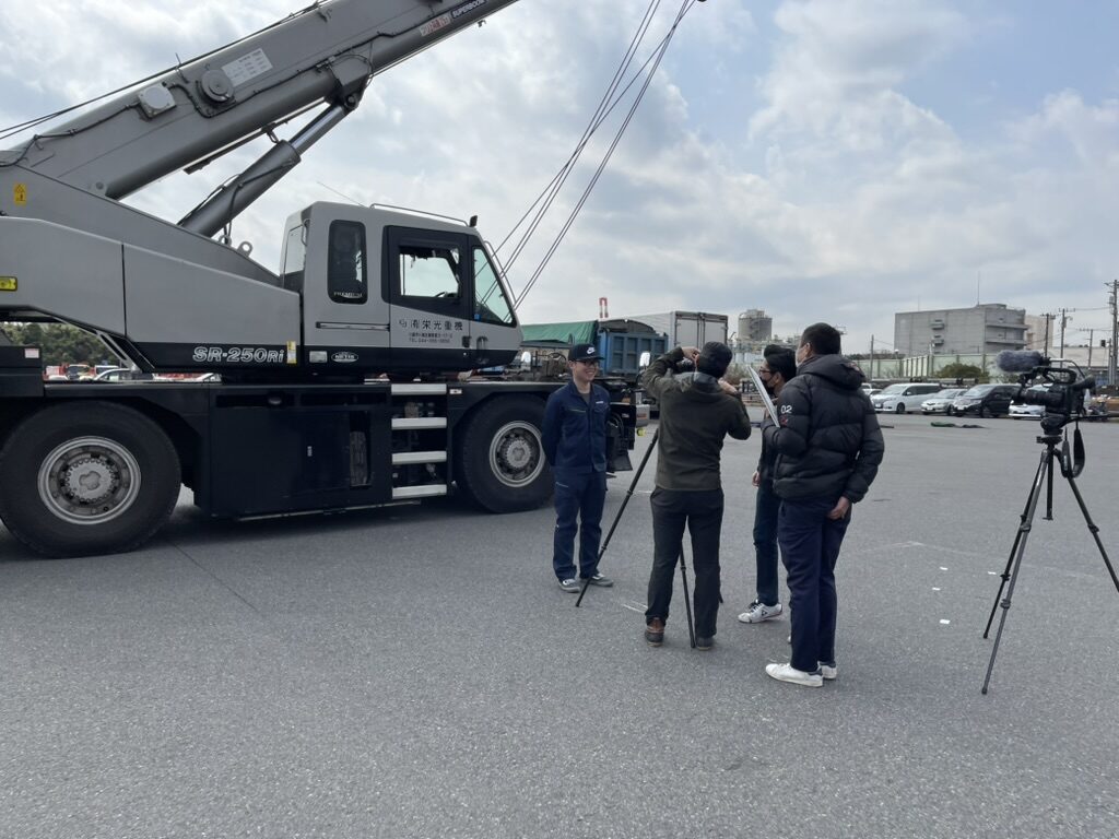 自社クレーンを前に撮影が行われている様子