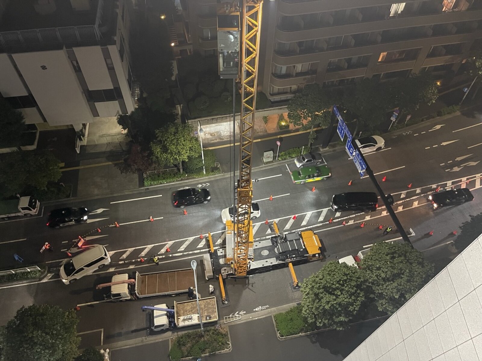 夜間の幹線道路で車線を規制し、大型クレーンを据えて作業しているところ